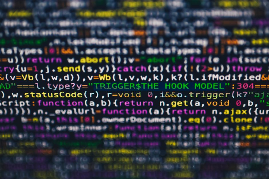 Software developer writing code with AI assistance on dual monitors