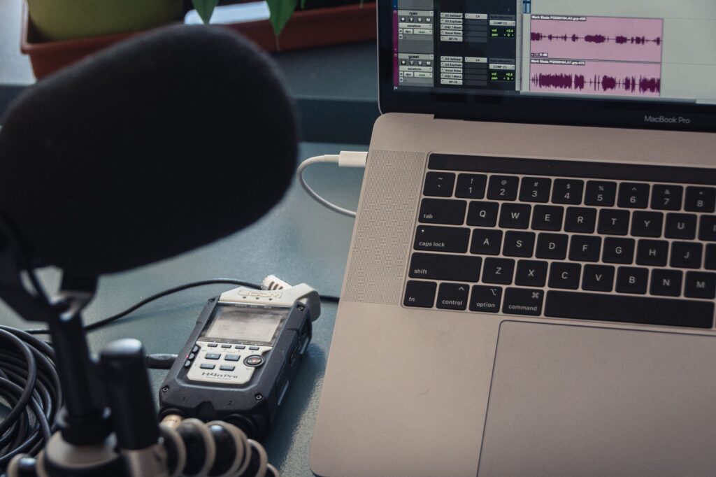 A condenser microphone beside a laptop on a desk in a home recording setup