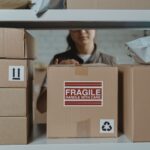 A person organizing fragile cardboard boxes in a warehouse setting.